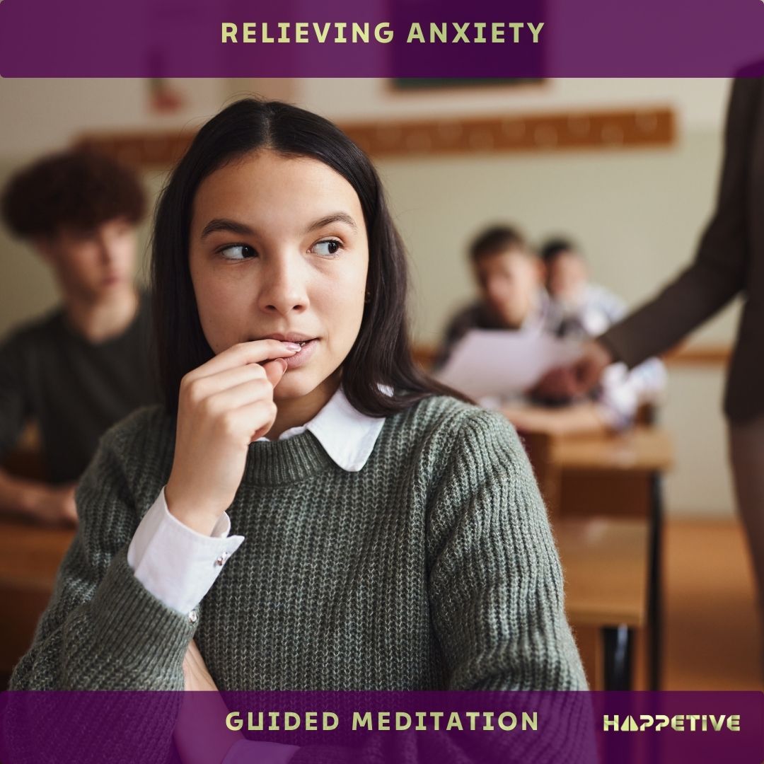 A young women sitting in a group of class feeling anxious before starting an exam. She will listen to relieving anxiety guided meditation to overcome her anxiety - Happetive